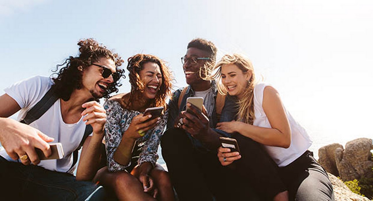 Group of people holding their mobile phones and laughing