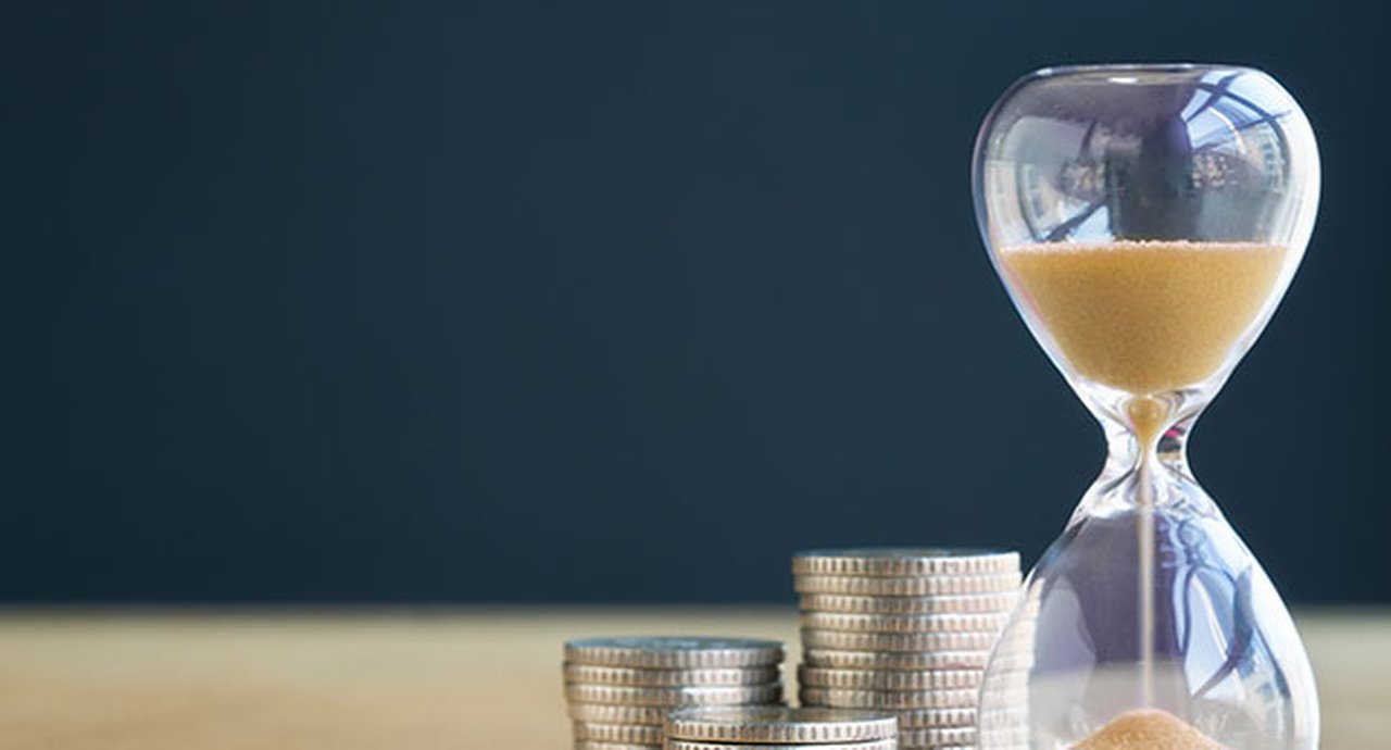 An hourglass next to a stack of coins