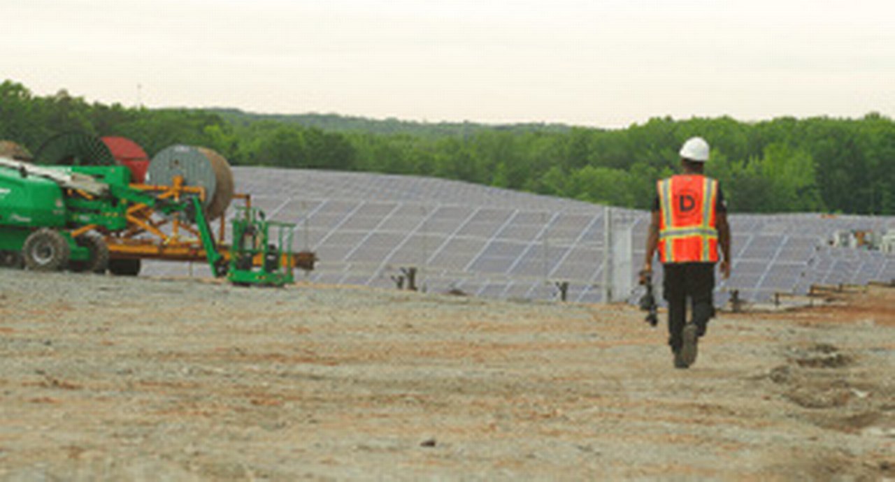 Construction site worker walking towards heavy machinery
