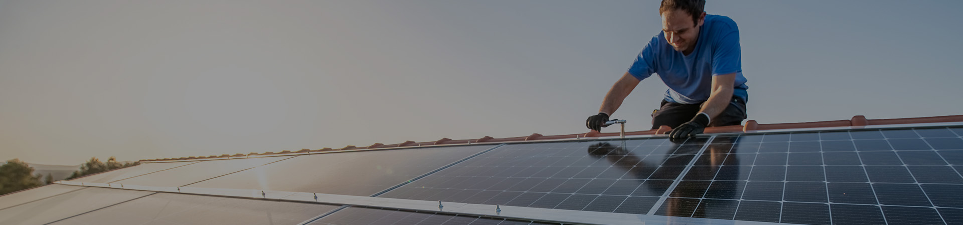 Kneeling professional fixing solar panels from the top of the roof of a house, side view of the roof with sun reflection close-up